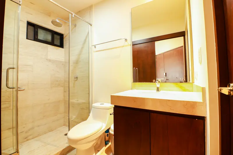Baño con regadera de cancel de vidrio y lavabo de mármol