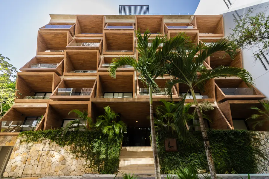 Fachada de L Condos con balcones revestidos en madera y palmeras